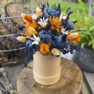 FlowerBox wypełniony suszonymi roślinami w odcieniach kobaltu i pamarańczy, z białymi elementami czarnuszki oraz kremowymi akcentami kanarów