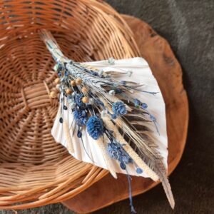 topper z suszonych kwiatów położony na koszyku wiklinowy